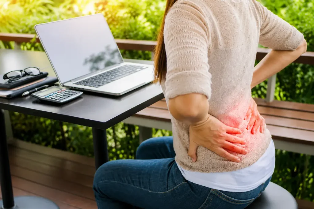 Acupuncture for Hot Flashes and Menopause Relief: A 2026 Evidence Guide 1 Woman experiencing lower back discomfort while working outdoors, representing acupuncture for hot flashes and natural relief from menopause-related pain and tension.