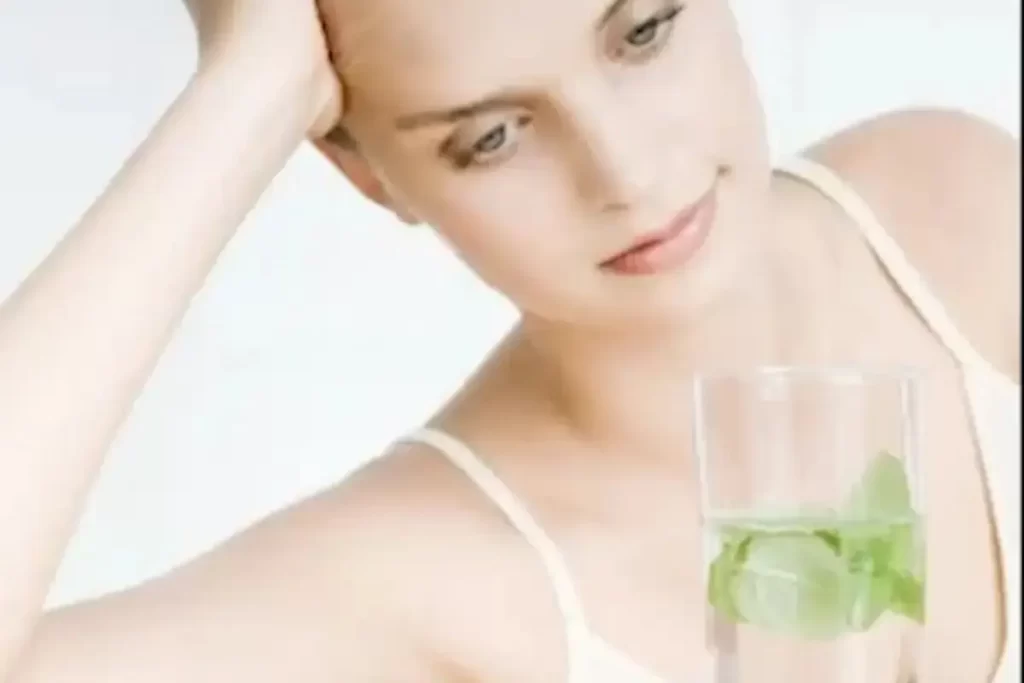 Woman drinking mint-infused water to help manage detox symptoms and stay refreshed.