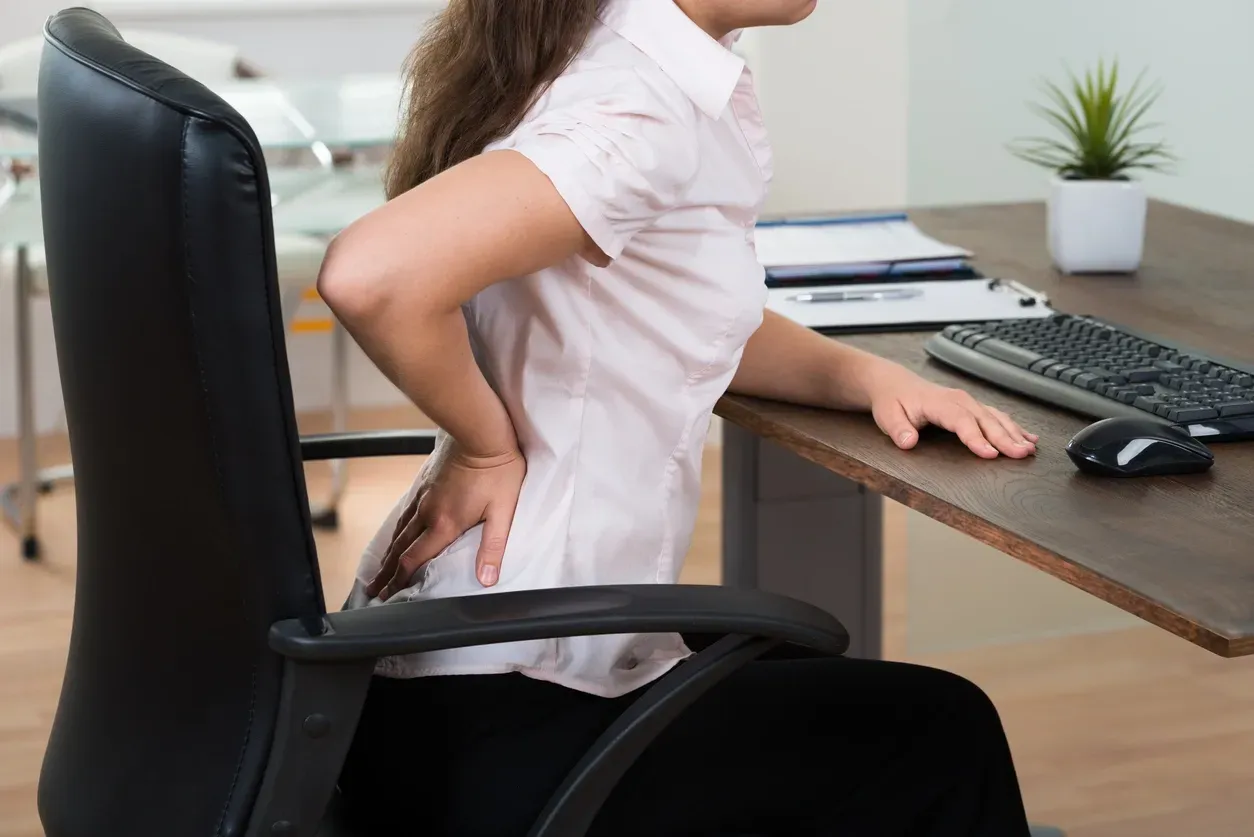 Desk worker experiencing lower-back pain while sitting