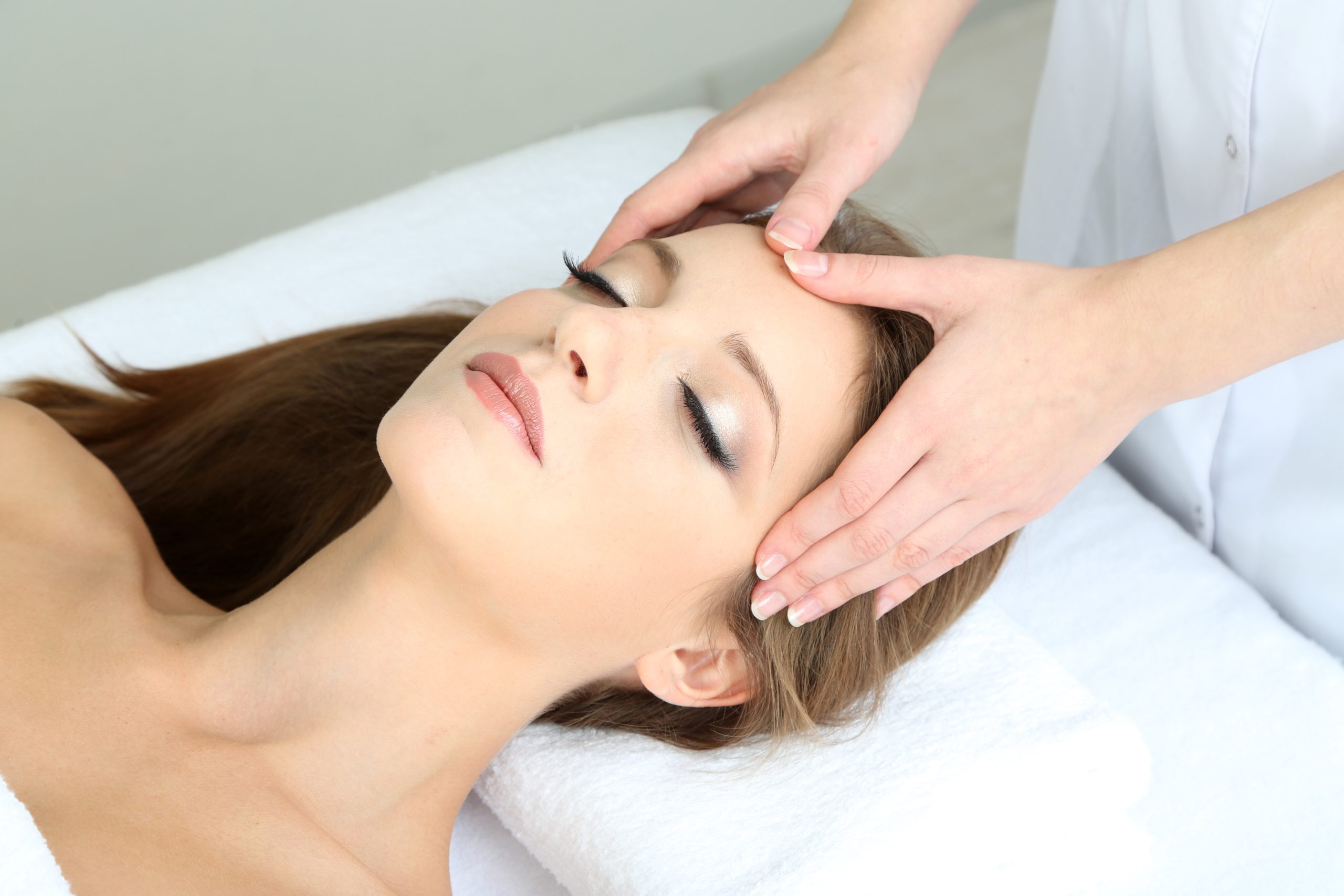 Beautiful young woman during facial massage in cosmetic salon cl