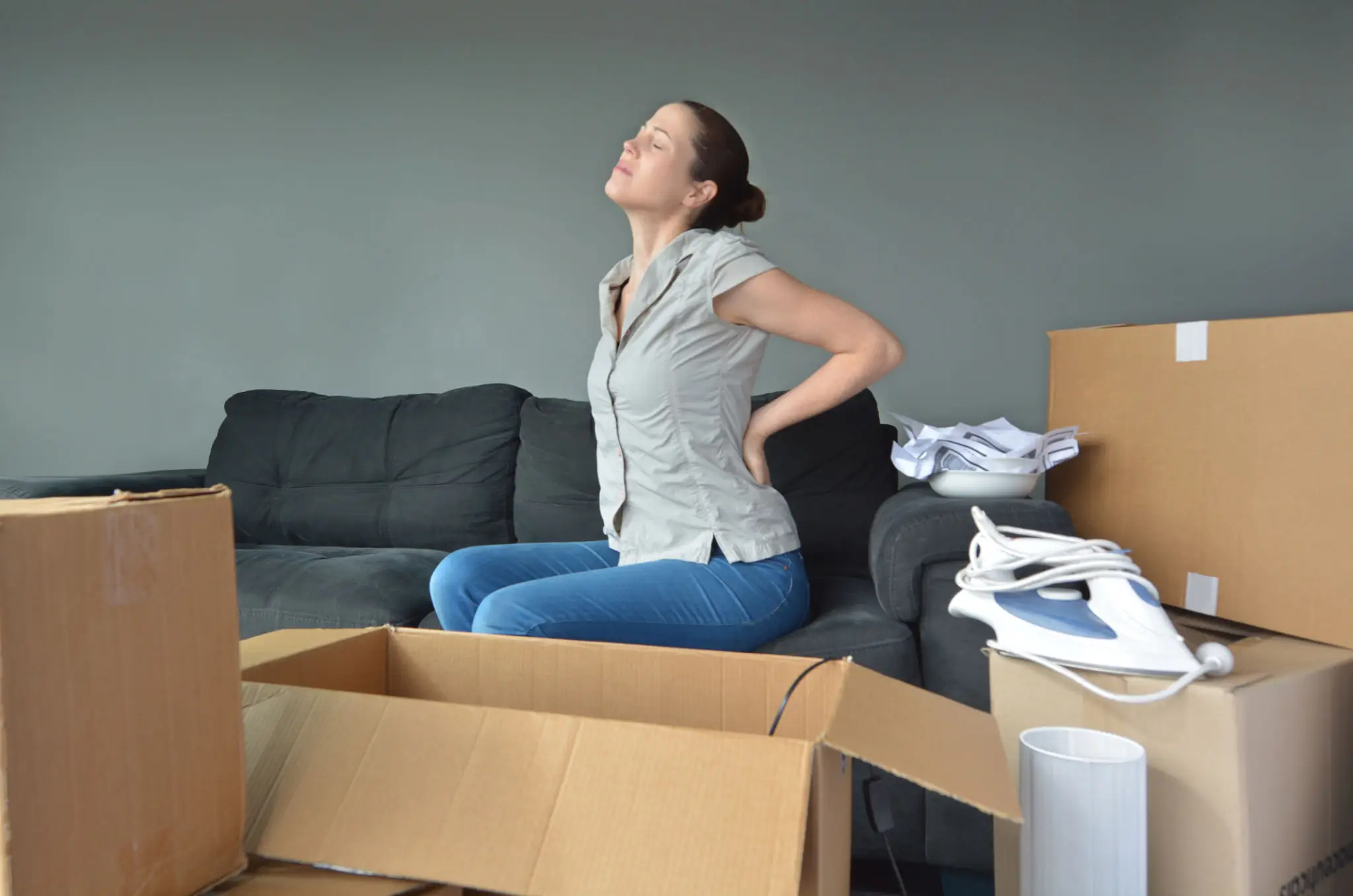 Woman experiencing acute low-back pain while moving boxes