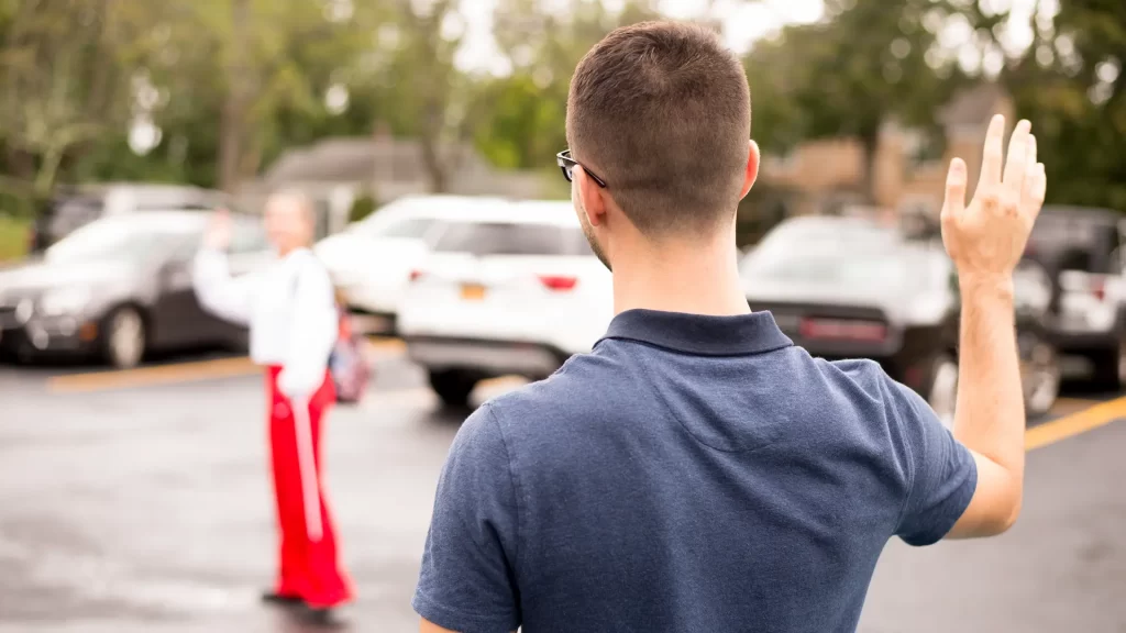 Person waving to a patient arriving in the clinic parking lot