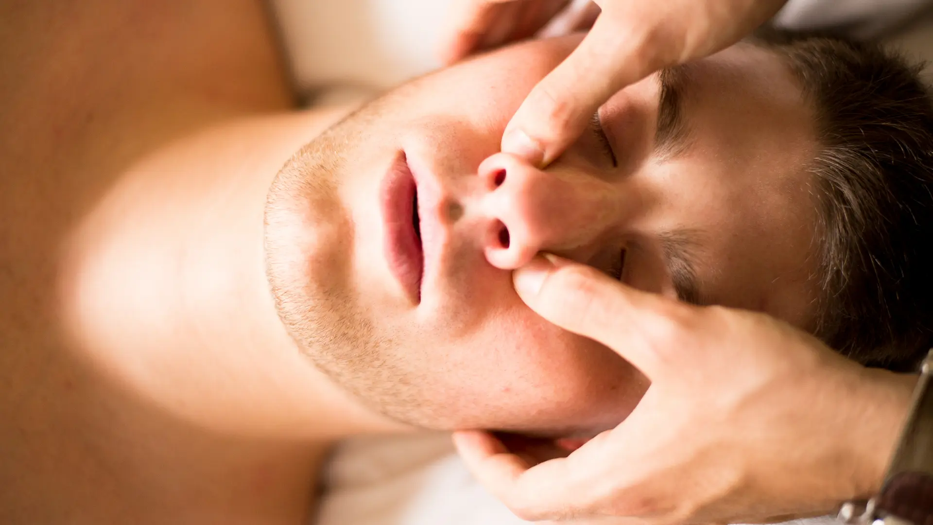 Therapist applying facial pressure point therapy to a patient's nose area