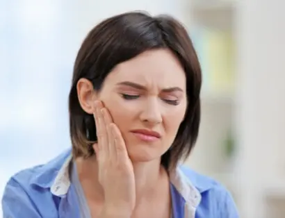 Woman holding jaw in pain, experiencing TMJ discomfort, representing treatment services at Messina Acupuncture in Setauket, NY