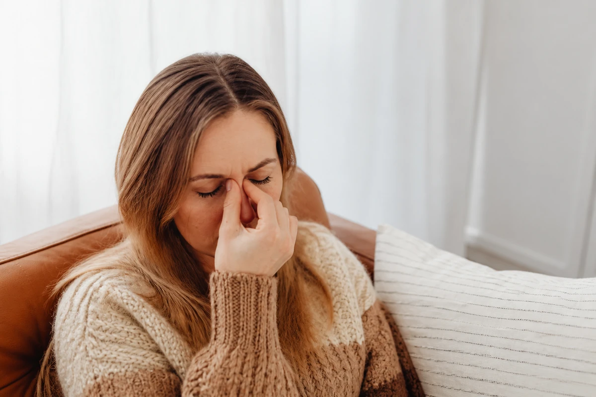 Adult experiencing facial pressure and headache symptoms during seasonal allergy season